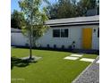 Charming single-story home boasts a modern front yard with synthetic grass and a vibrant yellow front door at 2201 N 29Th Pl, Phoenix, AZ 85008