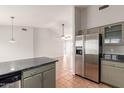 Open-concept kitchen with stainless steel refrigerator, grey cabinets, granite counters, and terracotta tile floors at 3050 E Pontiac Dr, Phoenix, AZ 85050