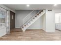 Open-concept living area with tile floors, staircase and a view of the front door and white cabinets at 4601 N 102Nd Ave # 1020, Phoenix, AZ 85037