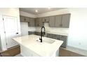 Modern kitchen with gray cabinetry, white countertops, a large island and stainless steel faucet at 5650 S 253Rd Ave, Buckeye, AZ 85326