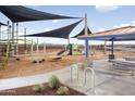 Community playground featuring swings, slides, and climbing structures with ample seating area and desert landscape at 5650 S 253Rd Ave, Buckeye, AZ 85326