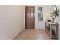 Welcoming foyer with a wood front door, neutral tile flooring, and a decorative console table at 7736 W Tumblewood Dr, Peoria, AZ 85382