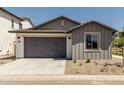 Home features low maintenance landscaping, gray two-car garage and a concrete driveway at 9416 E Sequence Ave, Mesa, AZ 85212