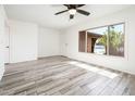 Bright bedroom with wood floors, a ceiling fan, and a large window with backyard views at 11030 N 47Th Ave, Glendale, AZ 85304