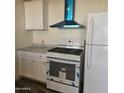 Bright kitchen featuring white cabinets, appliances, and a modern vent hood at 11411 N 91St Ave # 188, Peoria, AZ 85345