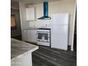 Bright kitchen featuring white cabinets, appliances, and a modern vent hood at 11411 N 91St Ave # 188, Peoria, AZ 85345