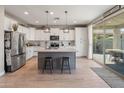 Modern kitchen featuring white cabinets, stainless steel appliances, an island, and a sliding glass door to the backyard at 12236 W Country Club Ct, Sun City, AZ 85373