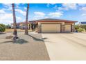 Charming home featuring a three-car garage, stone accents, and a meticulously landscaped front yard under a bright blue sky at 15532 W Prairie Dunes Dr, Surprise, AZ 85374