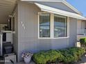 Close up of the home featuring a window with blinds, trimmed landscaping, and the house number 121 at 2233 E Behrend Dr # 121, Phoenix, AZ 85024