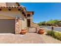 Home's exterior featuring an arched gate, brick-paved walkway, and desert landscaping at 3030 N Saranac --, Mesa, AZ 85207