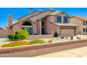 Charming two-story home featuring well-manicured desert landscaping, with green shrubs and flowers at 7725 W Dreyfus Dr, Peoria, AZ 85381