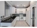 Well-lit kitchen with white cabinetry, black countertops, and stainless steel appliances at 813 E Agua Fria Ln, Avondale, AZ 85323