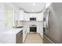 Kitchen boasts stainless steel appliances, white cabinetry, white counters, and new hardwood flooring at 8341 E Keim Dr, Scottsdale, AZ 85250