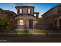 Charming two-story home at twilight featuring a cozy front porch with stone accents and a well-manicured front yard at 13465 N 158Th Ave, Surprise, AZ 85379