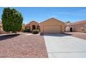 Charming single-story home featuring a two-car garage and desert landscaping with a beautiful green tree at 17910 N 92Nd Ln, Peoria, AZ 85382