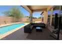 Relaxing covered outdoor patio with a gray sectional sofa, swimming pool and well-manicured lawn at 3063 N Heritage St, Buckeye, AZ 85396