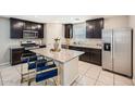 Modern kitchen featuring dark wood cabinets, stainless steel appliances, granite countertops and island seating at 3916 S 79Th Ln, Phoenix, AZ 85043