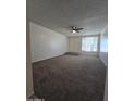 Open concept living room with plush neutral carpet, white walls, a ceiling fan fixture, and natural light at 8936 W Mackenzie Dr, Phoenix, AZ 85037