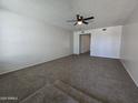 Spacious living room featuring plush neutral carpet, white walls, and contemporary ceiling fan fixture at 8936 W Mackenzie Dr, Phoenix, AZ 85037