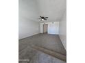 Spacious living room featuring plush neutral carpet, white walls, and contemporary ceiling fan fixture at 8936 W Mackenzie Dr, Phoenix, AZ 85037