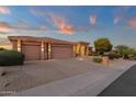 Wide driveway leading to a three-car garage, complemented by desert landscaping and soft outdoor lighting at 15600 E Robin Dr, Fountain Hills, AZ 85268