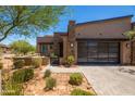 Modern home with sleek design, desert landscaping, a glass garage door, and a stone accent wall for an upscale look at 16134 E Ridgestone Dr, Fountain Hills, AZ 85268