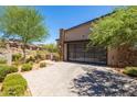 Modern home with sleek design, desert landscaping, a glass garage door, and a stone accent wall for an upscale look at 16134 E Ridgestone Dr, Fountain Hills, AZ 85268