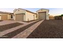 Home exterior featuring a three-car garage with gravel landscaping and a brick paver driveway at 18371 W Roma Ave, Goodyear, AZ 85395