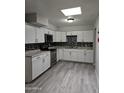 Modern kitchen boasts sleek white cabinets, stainless steel appliances, and eye catching black and white mosaic tile backsplash at 2019 E Southern Ave, Phoenix, AZ 85040