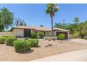 Single-story home with desert landscaping, a two-car garage, and green shrubbery at 6417 E Kings Ave, Scottsdale, AZ 85254