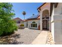 Charming single Gathering home entrance with stone walkway, well maintained desert landscaping, and an ornate door at 7108 W Morrow Dr, Glendale, AZ 85308