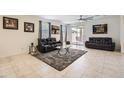 Spacious living room with neutral tile flooring, ceiling fan, and sliding glass doors at 7665 W Fetlock Trl, Peoria, AZ 85383