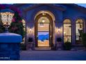 Elegant home entrance featuring a decorative iron gate, arched doorway, and manicured plants at 11773 E Desert Trail Rd, Scottsdale, AZ 85259