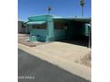 Turquoise mobile home featuring a covered carport and well-maintained gravel landscaping at 150 S Windsor Dr # 35, Mesa, AZ 85204