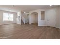 Spacious living room boasting hardwood floors, neutral paint, lots of windows, and open access to staircase and other rooms at 18123 W Lundberg St, Surprise, AZ 85388