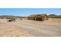 Wide shot of tan single-Gathering home with brown garage door and matching door surrounded by a desert landscape at 21859 W Gail Dr, Buckeye, AZ 85326