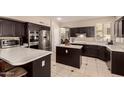 Well-lit kitchen with stainless steel appliances, dark wood cabinets and tile flooring at 1343 E Amberwood Dr, Phoenix, AZ 85048