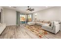 Bright living room featuring a large sectional sofa, wood-look tile floors, and sliding glass doors to the patio at 32611 N 20Th Dr, Phoenix, AZ 85085