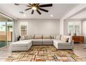 Spacious living room featuring a large sectional sofa, ceiling fan and wood-look tile floors with natural light at 32611 N 20Th Dr, Phoenix, AZ 85085