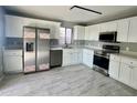 Modern kitchen with stainless steel appliances, white cabinets, and gray tile floors at 4104 N 113Th Ave, Phoenix, AZ 85037