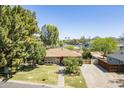 Charming single-story home with a well-manicured lawn, mature trees, and a brick driveway leading to a wooden gate at 1274 E Edgemont Ave, Phoenix, AZ 85006