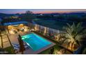 Aerial view of the pool, seating areas, and outdoor kitchen in a beautifully landscaped backyard at dusk at 17018 W Saguaro Park Ln, Surprise, AZ 85387