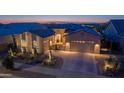 Charming desert home featuring meticulous landscaping, multi-car garage, and inviting curb appeal at dusk at 17018 W Saguaro Park Ln, Surprise, AZ 85387
