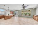 Spacious living room featuring elegant chandelier, tile flooring, and natural light streaming through multiple windows at 26135 N Desert Mesa Dr, Surprise, AZ 85387