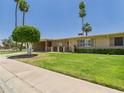 Inviting single-story home with well-manicured lawn, mature trees, and a welcoming front entrance at 9915 W Mountain View Rd, Sun City, AZ 85351
