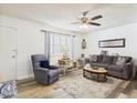 Cozy living room showcasing wood-look floors, a plush sofa, and ample natural light from a window at 9915 W Mountain View Rd, Sun City, AZ 85351