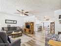 Bright living room featuring wood-look floors, neutral paint, and an open layout to the dining area at 9915 W Mountain View Rd, Sun City, AZ 85351