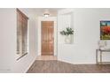 Inviting entryway features a wooden door, neutral tile, and light-filled ambiance with wood-style laminate flooring at 1086 E Canyon Trail --, San Tan Valley, AZ 85143