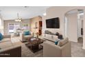 Bright living room with neutral tones, plush carpet, and a large TV at 1623 E Maplewood Ave, Buckeye, AZ 85326