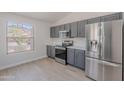 Bright kitchen featuring stainless steel appliances, granite countertops, gray cabinets, and wood-look floors at 23852 W La Salle St, Buckeye, AZ 85326